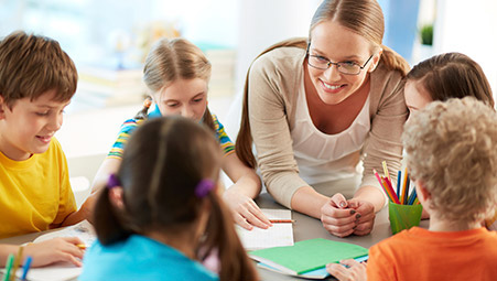 teacher with young students around a work table