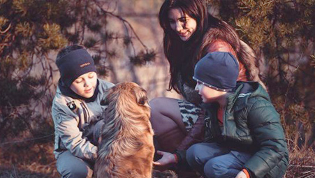 mother with two children and their dos in winter clothes taking a walk outdoors