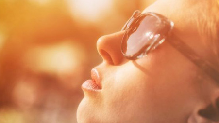 young girl in sunglasses basking in the light of the sun
